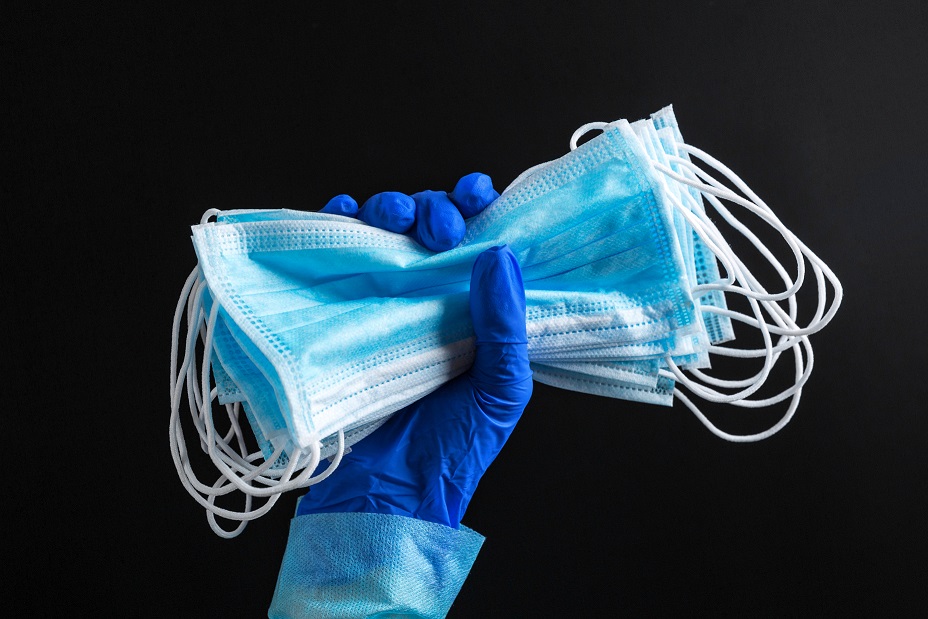 Hand in medical glove is holding a bunch of protective masks at black background. Coronavirus concept. Healthcare concept.